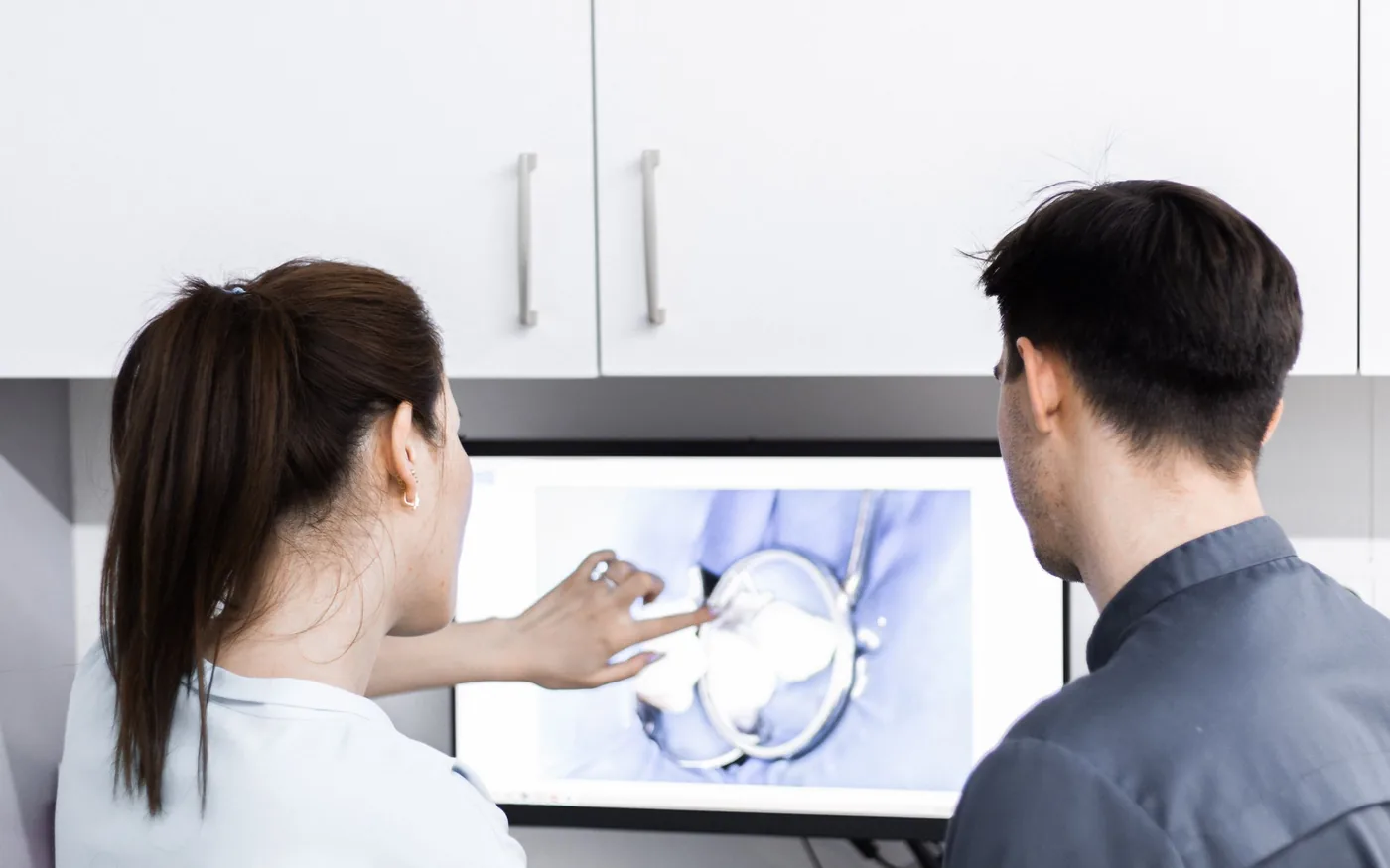 Two dental professionals reviewing a 3D tooth on a computer screen