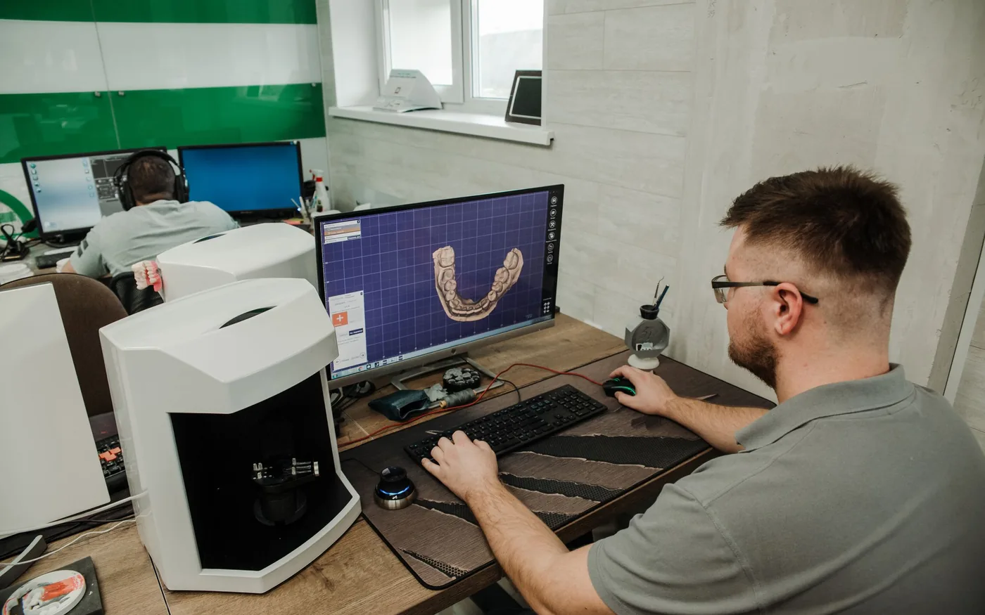 Dental technician working with dental CAD software at a computer workstation